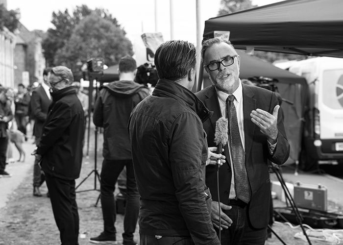 candid street photo of a group of journalists and news reporters speaking outdoors