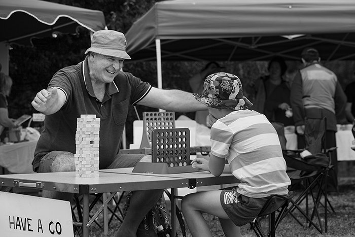 candid street photo of a father and son playing connect four outdoors
