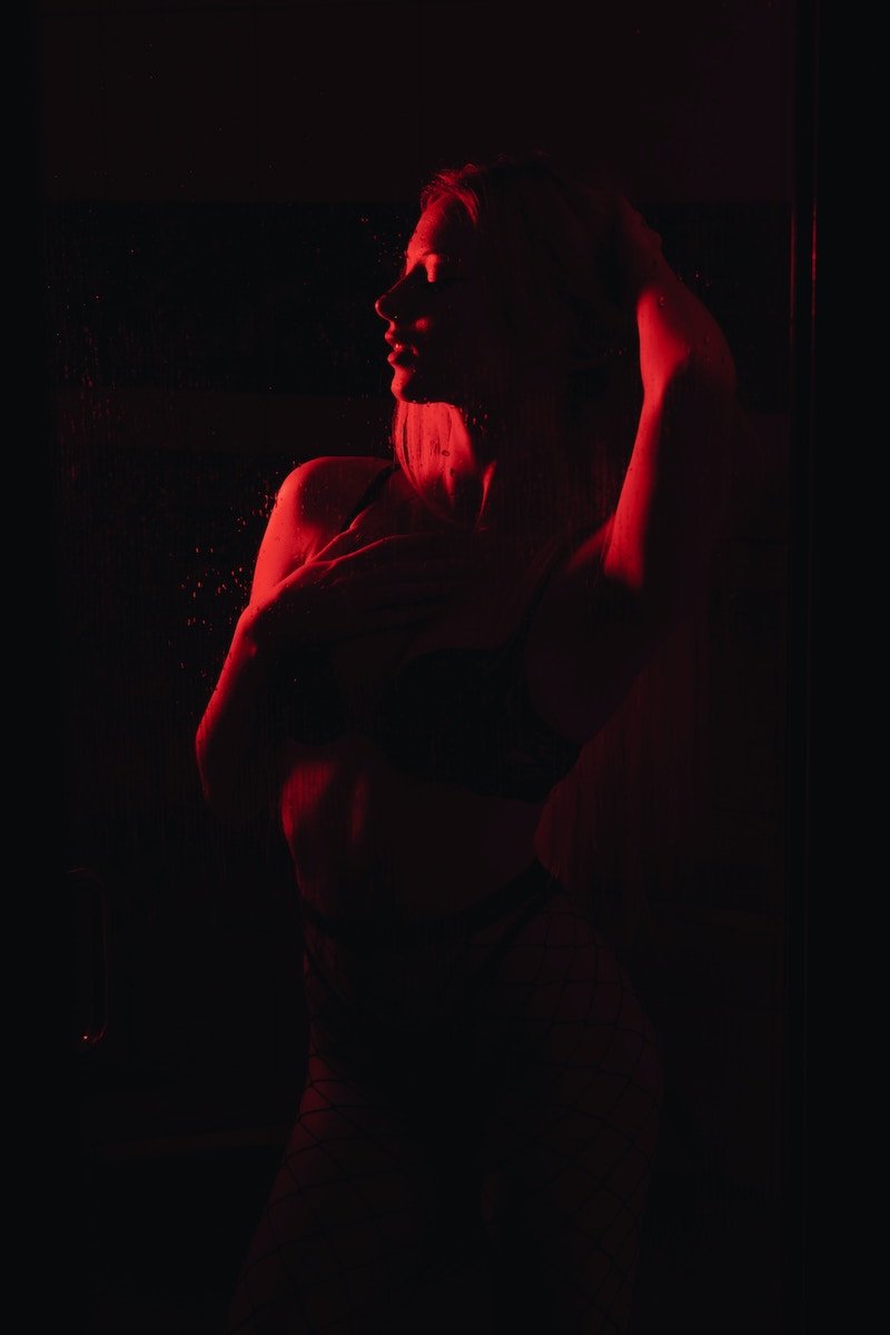 Boudoir shoot with a woman posing under red lighting