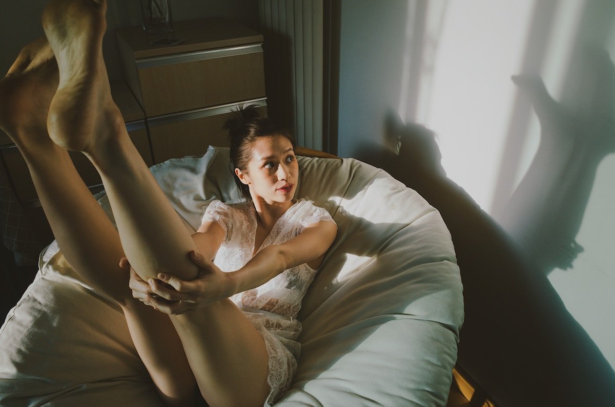 A woman sitting with her legs up for a boudoir photography photoshoot