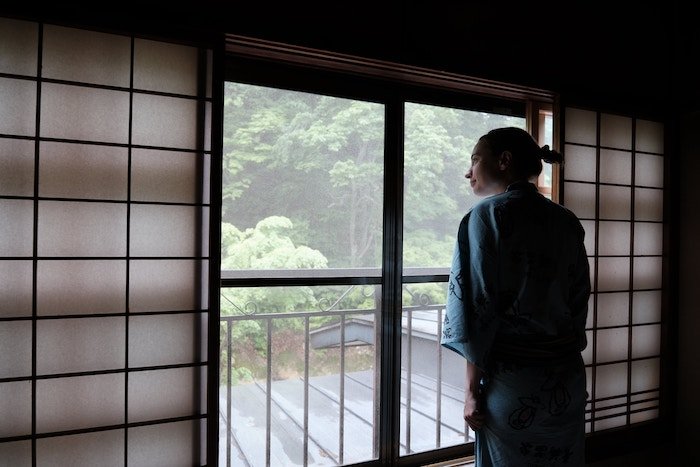 A person looking out a window on a cloudy day.