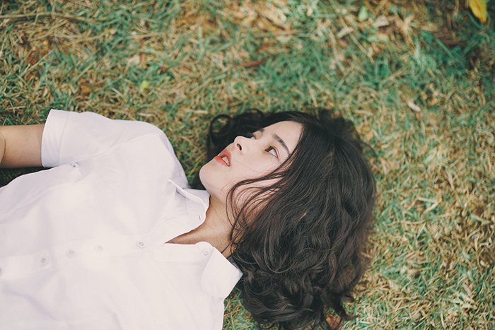 a minimalist portrait of a female model lying on the grass