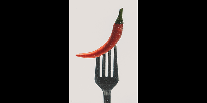 A chili pepper on a fork setup to shoot colorful paint in water photography