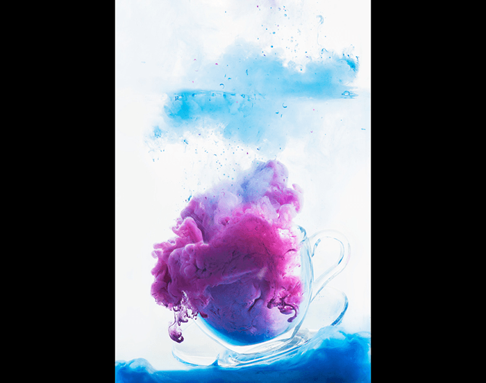 A teacup filled with two different acrylic clouds for colorful paint in water photography