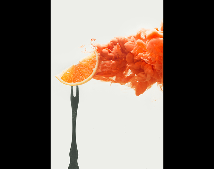 An orange slice on a fork setup to shoot colorful paint in water photography
