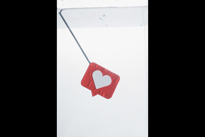 A knitting needle attached to a heart icon submerged to shoot colorful paint in water photography