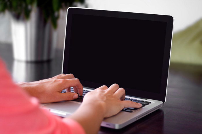 a professional photographer working on portrait photography pricing guide on a laptop in a home office 