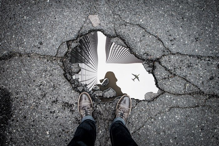 a photographers shoes and reflection in a puddle - symbolism in photography