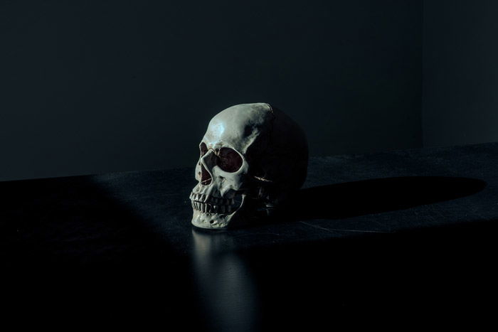 atmospheric photo of a human skull on black background - symbolism in photography