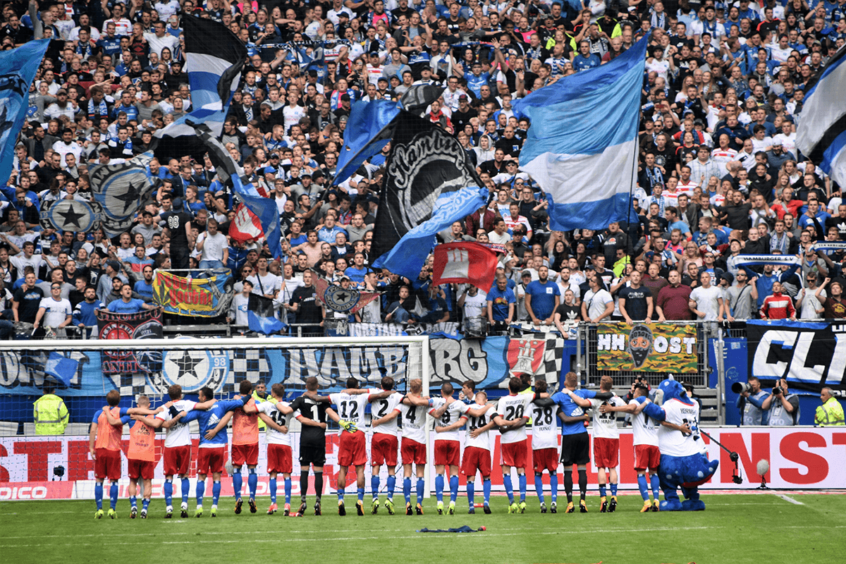 Players lined up on the pitch in front of raucous fans as an example of soccer photography