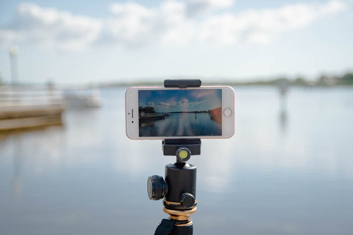 An iPhone set up on a tripod looking over water during the day for time-lapse photography