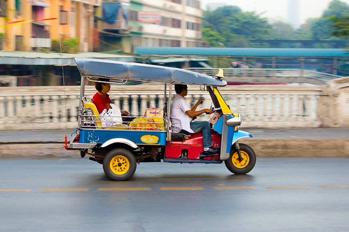 A freeze motion photography shot of a colorful tuktuk racing through the city 