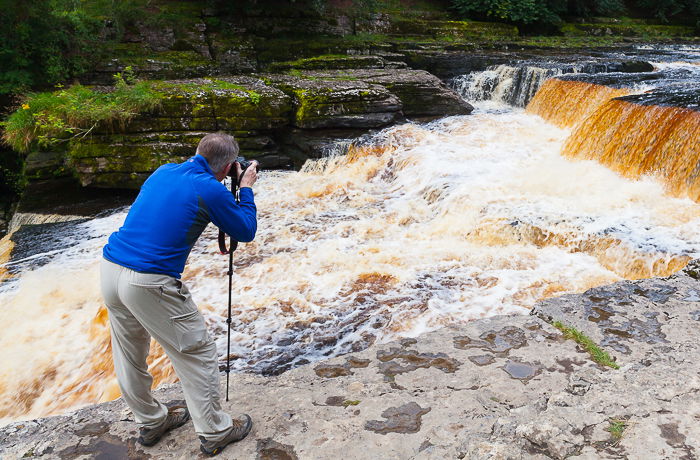 a photographer attempting a freeze motion photography shot of a waterfall