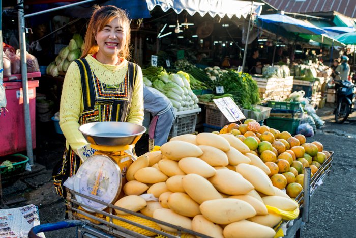 a smiling outdoor market vendor with incident light falling on her face 