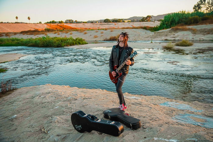 Photo of a man playing the guitar on a riverside