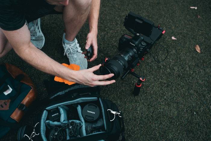 a photographer setting up a Canon dSLR camera with a Tamron lens with Abbreviations