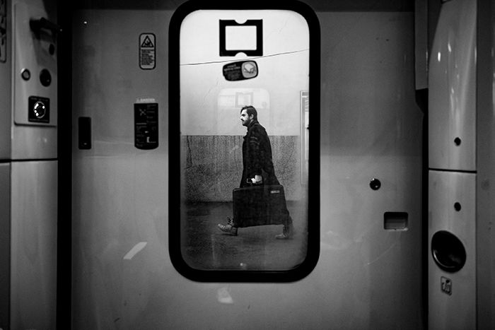 Photo of a man walking with a suitcase reflecting in a mirror