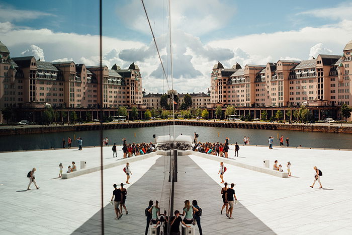 Photo of a square and buildings reflecting on the glass walls of an office building