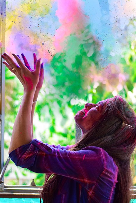 Side-view photo of agirl throwing rainbow color powder in the air, fast shutter speed 