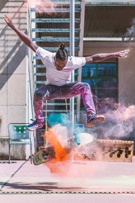 Photo of a man doing a skateboarding trick with orange color powder