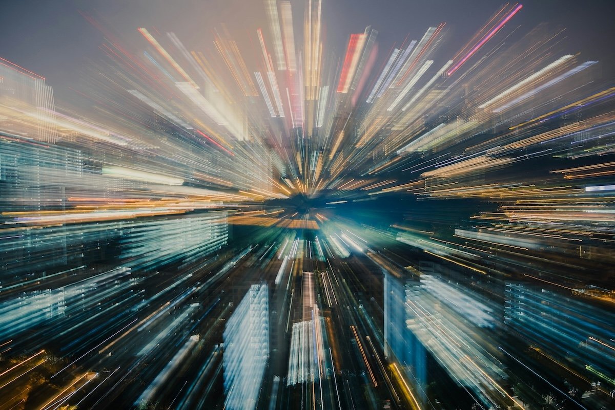 An artistic zoom burst shot with abstract converging lines over a blurry cityscape made with intentional camera movement