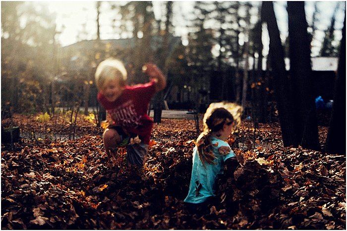 Photo of children playing with autumn leaves