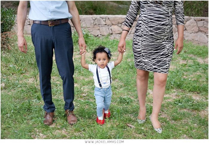 sweet family portrait of parents holding a little girls hand outdoors