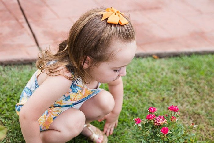 lifestyle portrait of a little girl crouching on the grass