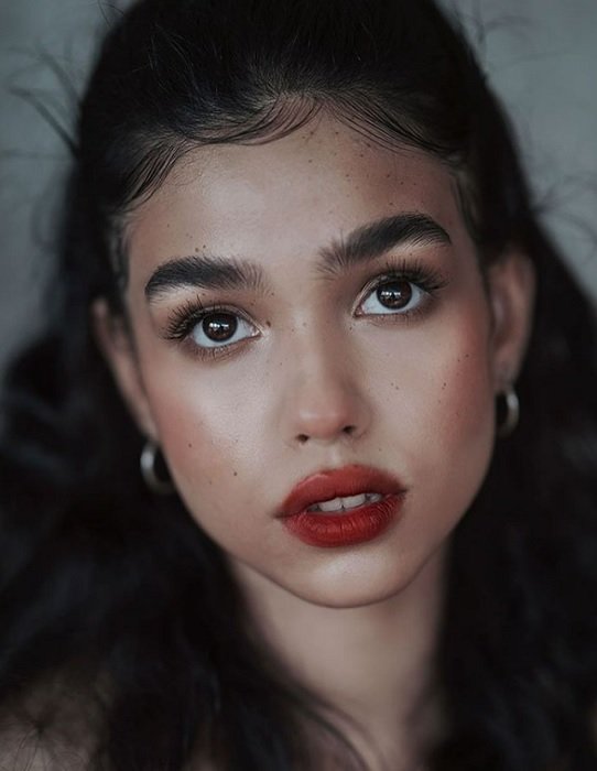 Close portrait of girl with dark hair, brown eyes, and red lips