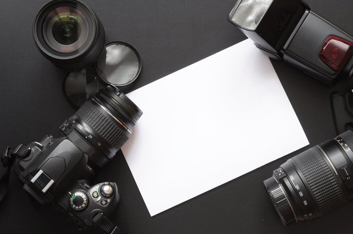 Photo of a camera, lenses, and a white sheet of paper