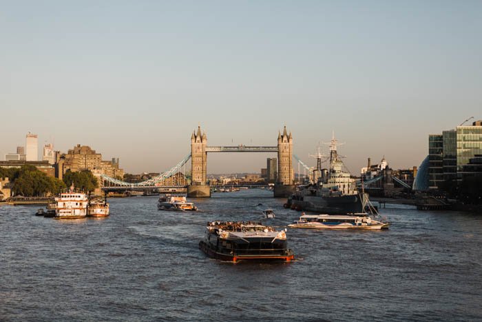 Photo of ships on the Thames river with the London Bridge in the background