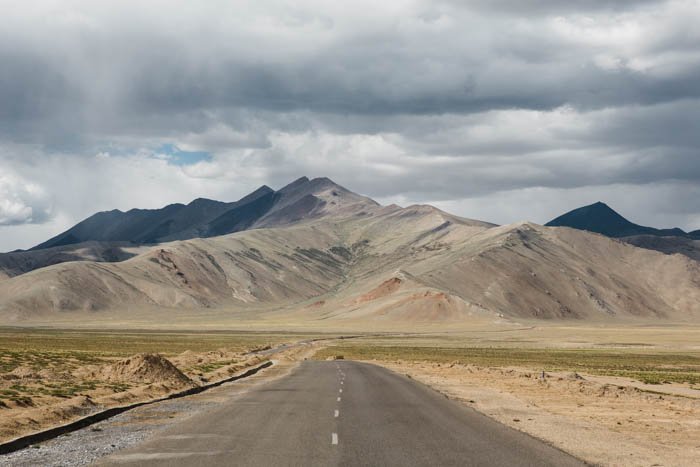Photo of a road with mountains in the background leading lines