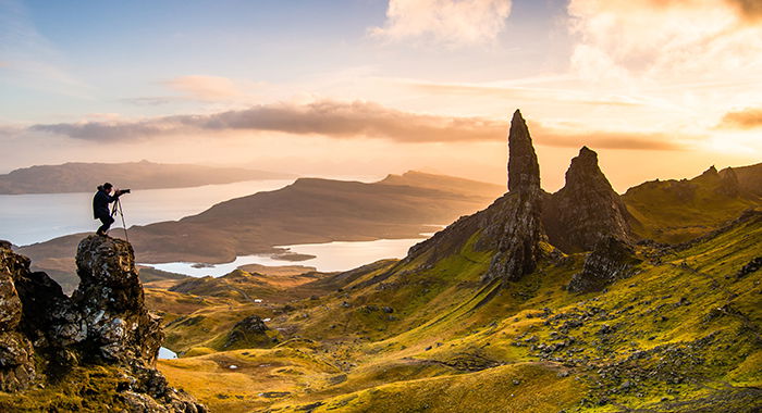 A landscape image with a photographer taking a photo on the left hand side. 