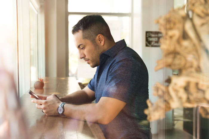 a man using his smartphone at a wooden counter