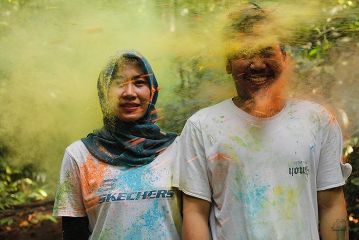 A couple posing outdoors covered in colored powder