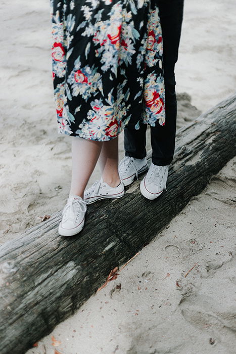 a close up of a couples legs balancing on a wooden beam