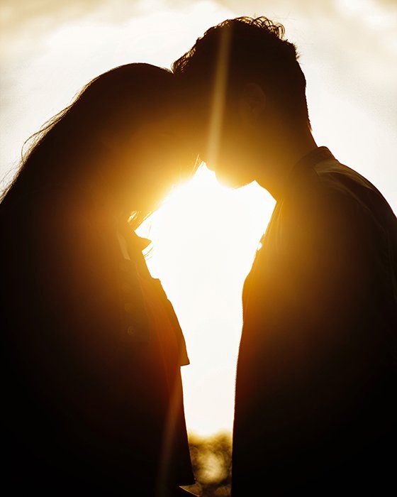 Silhouette of a couple embracing in front of a sunset