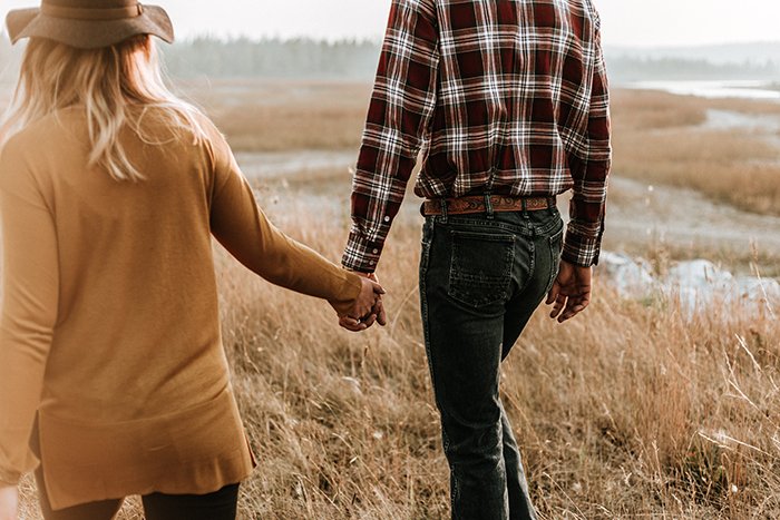 A couple holding hands and walking through the countryside 