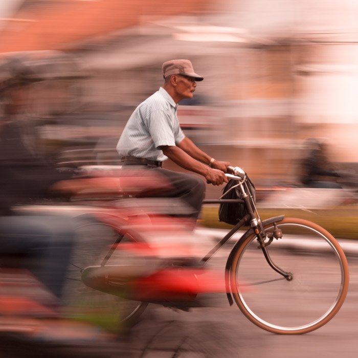 Photo of an older man cycling with motion blur effect