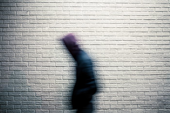 A person walking in front of a wall, captured with motion blur 