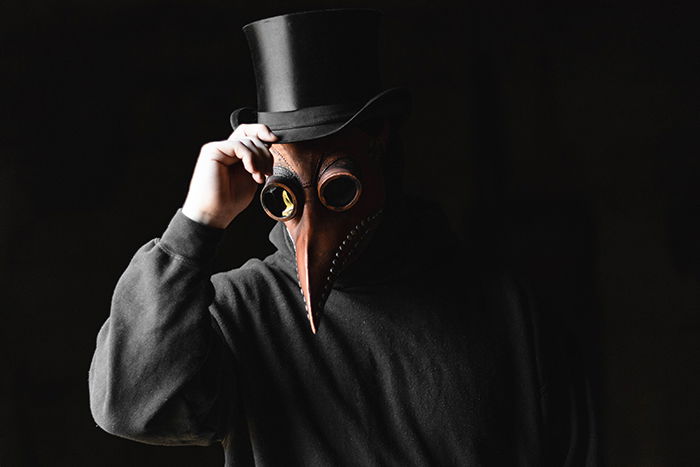 A person in a scary mask in front of a black background 