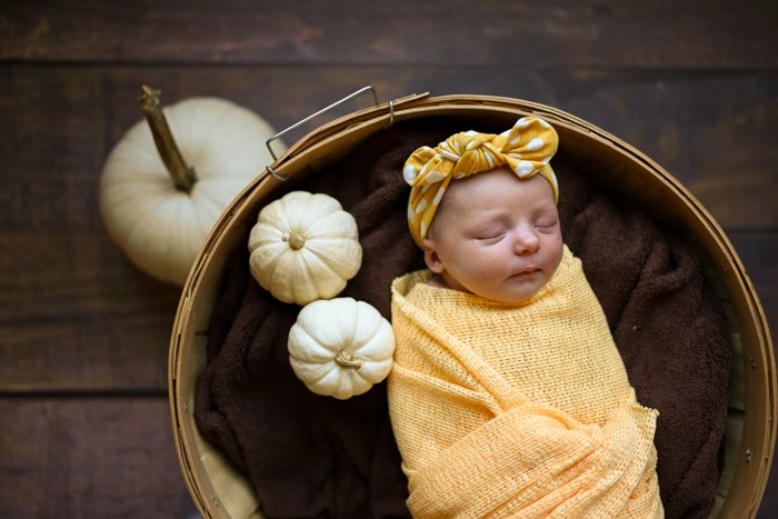 Photo of a baby sleeping with pumpkins around