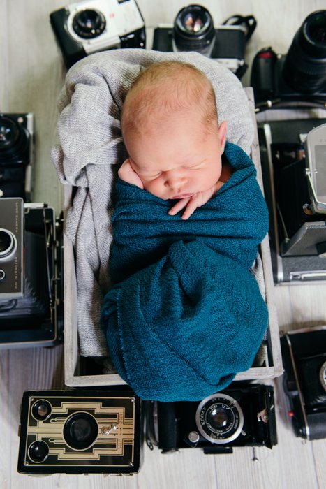 Photo of a baby sleeping with old cameras around him