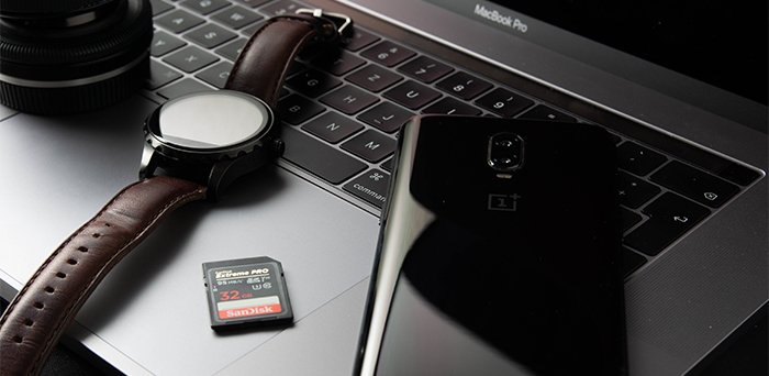 A wristwatch, a mobile phone, and a memory card on an open laptop 