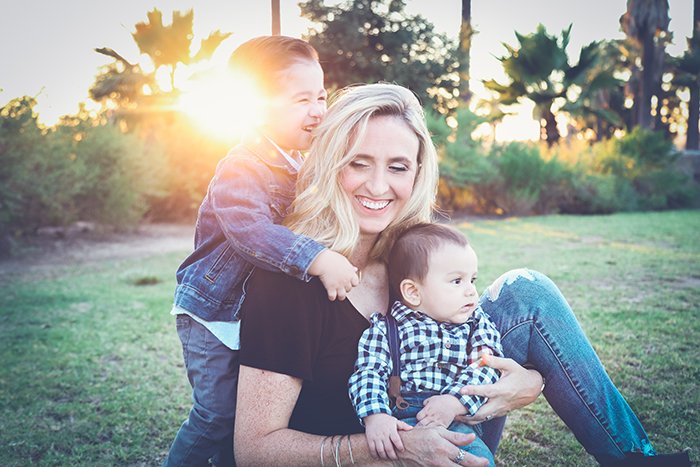 a sweet mommy and me photoshoot of a mother and two young sons playing outdoors