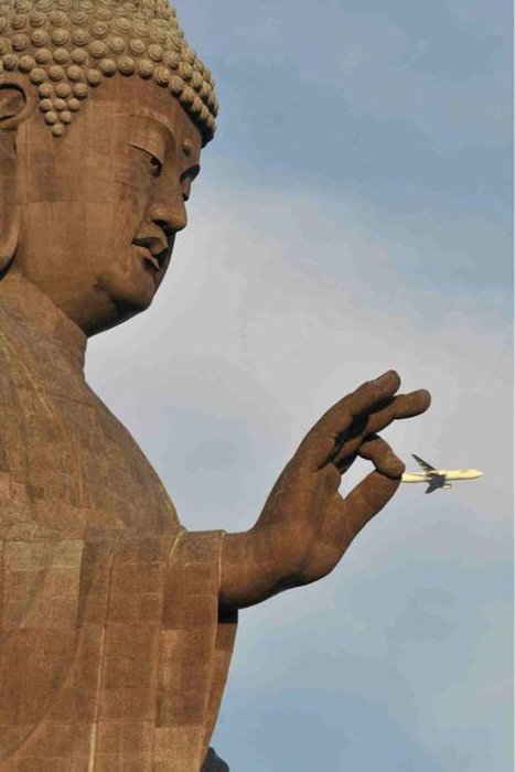 Photo of a Buddha statue looking like it is holding a plane