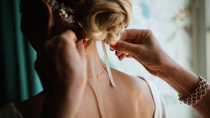 Photo of a woman adjusting a bride's headpiece