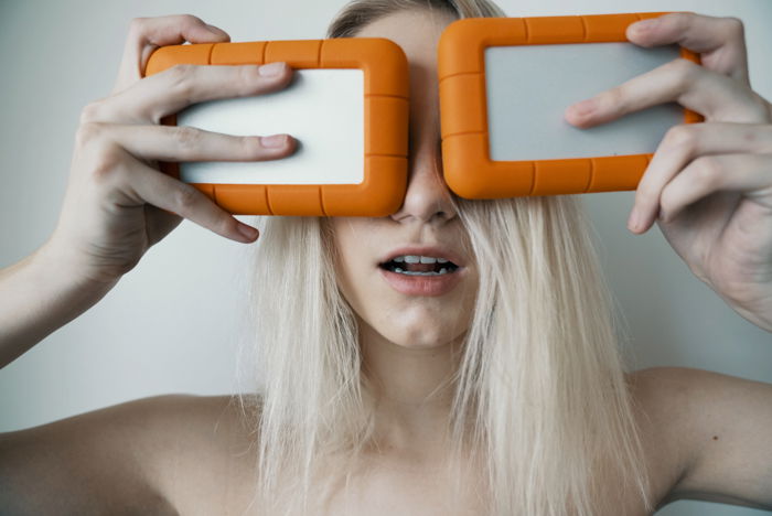 Photo of a woman holding two external drives in front of her face