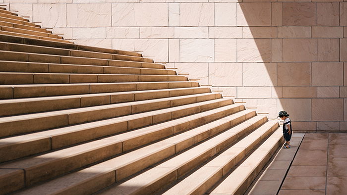 Photo of a small kid in front of a stairway with many steps