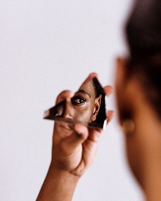 A woman's face reflecting in a broken piece of mirror